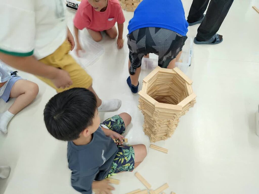 北日野自治振興会 カプラで作った筒状の作品を囲む子どもたち