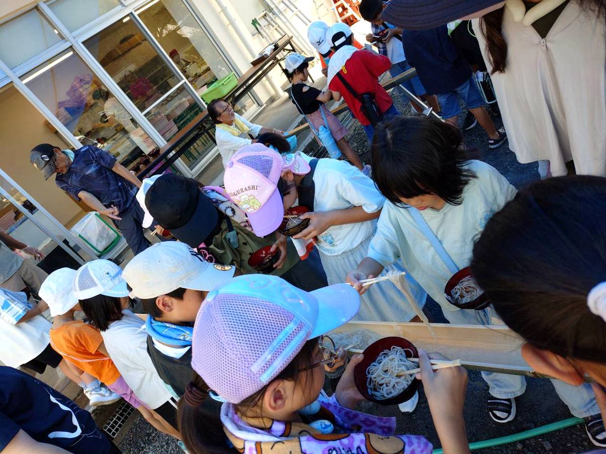 北日野自治振興会 流れてくるそうめんを箸ですくう子どもたち