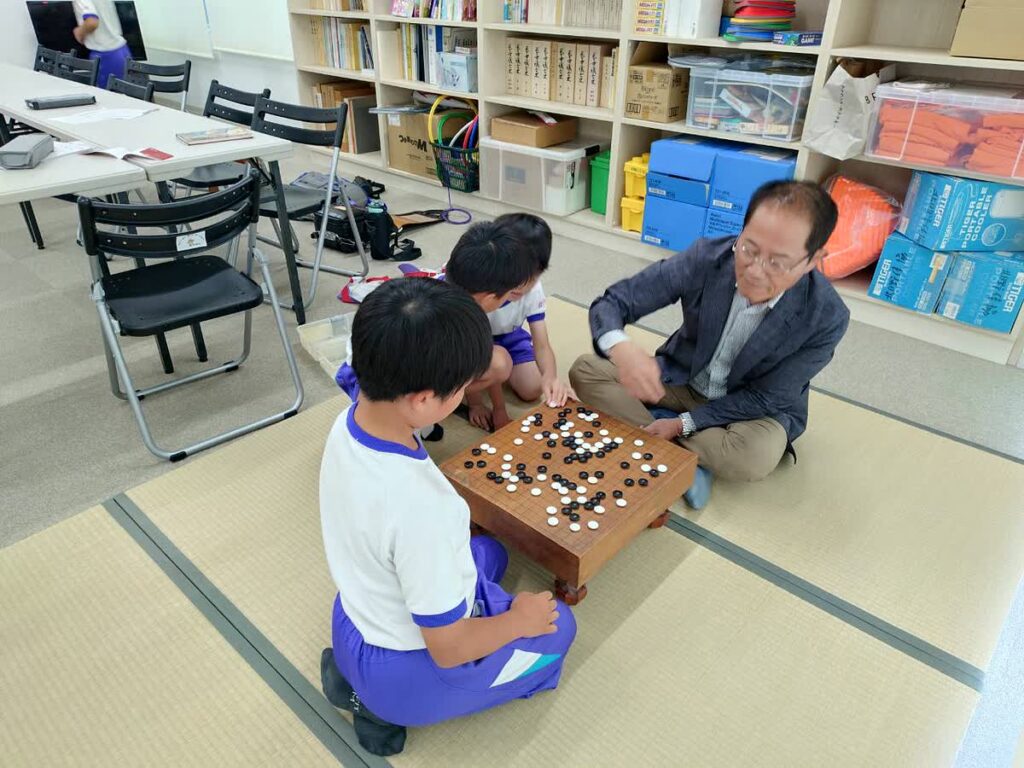 北日野自治振興会 囲碁教室で講師と対局する子どもたち