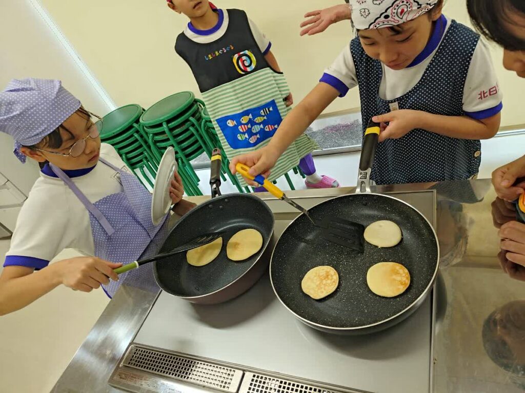 北日野自治振興会 料理教室でフライパンを使ってパンケーキを焼く子どもたち