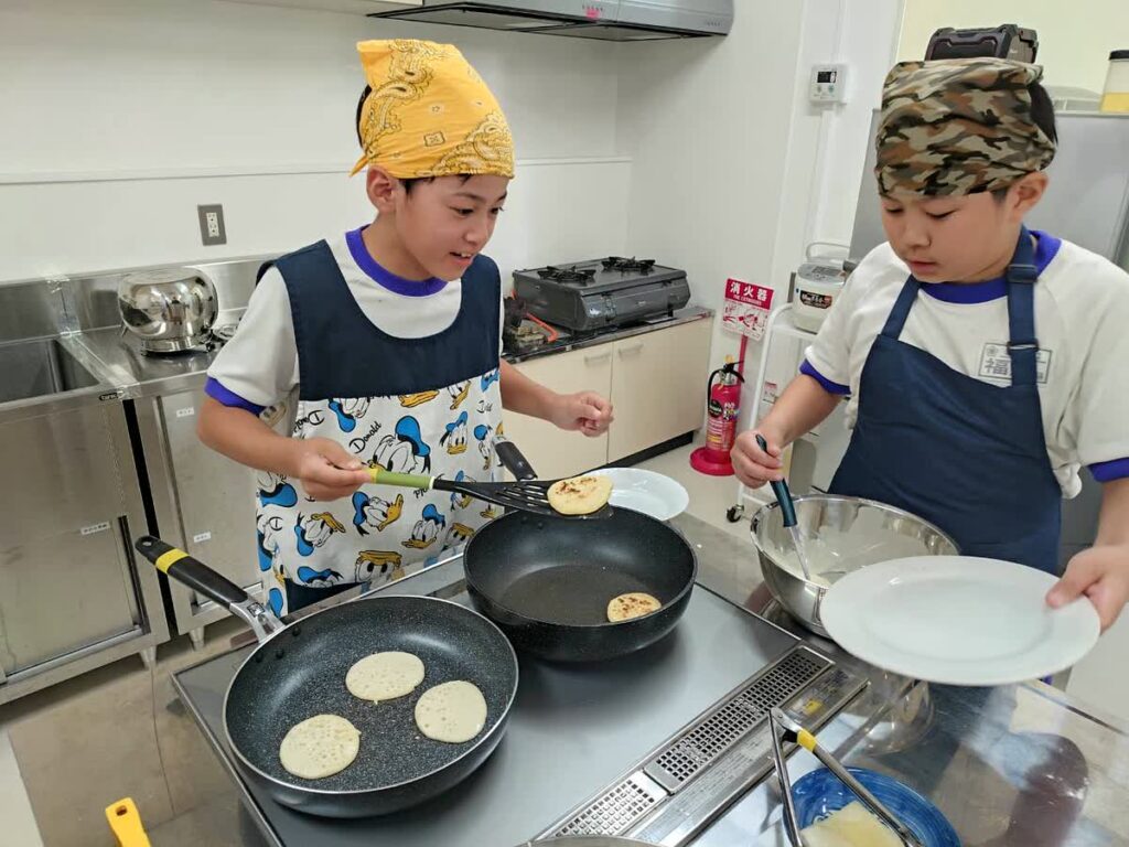 北日野自治振興会 料理教室で焼き上がったパンケーキを皿に移す子どもたち