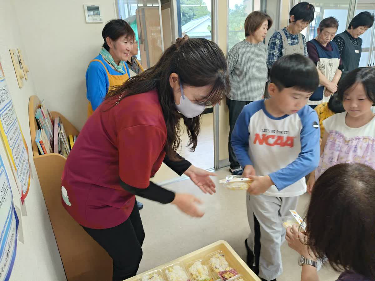 北日野自治振興会 赤十字奉仕団の皆さんから料理を受け取る子どもたち